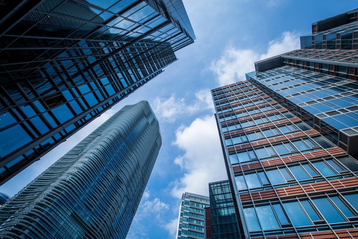 Bottom view of modern skyscrapers in business district against blue sky