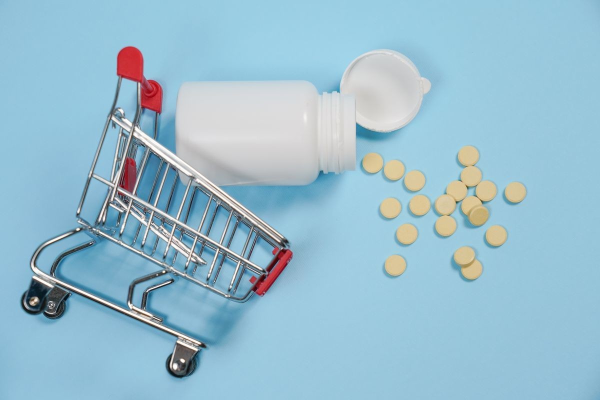 Pills in shopping cart on blue background. The concept: trade in medicines, pharmacies. Copy spase, spase for text.